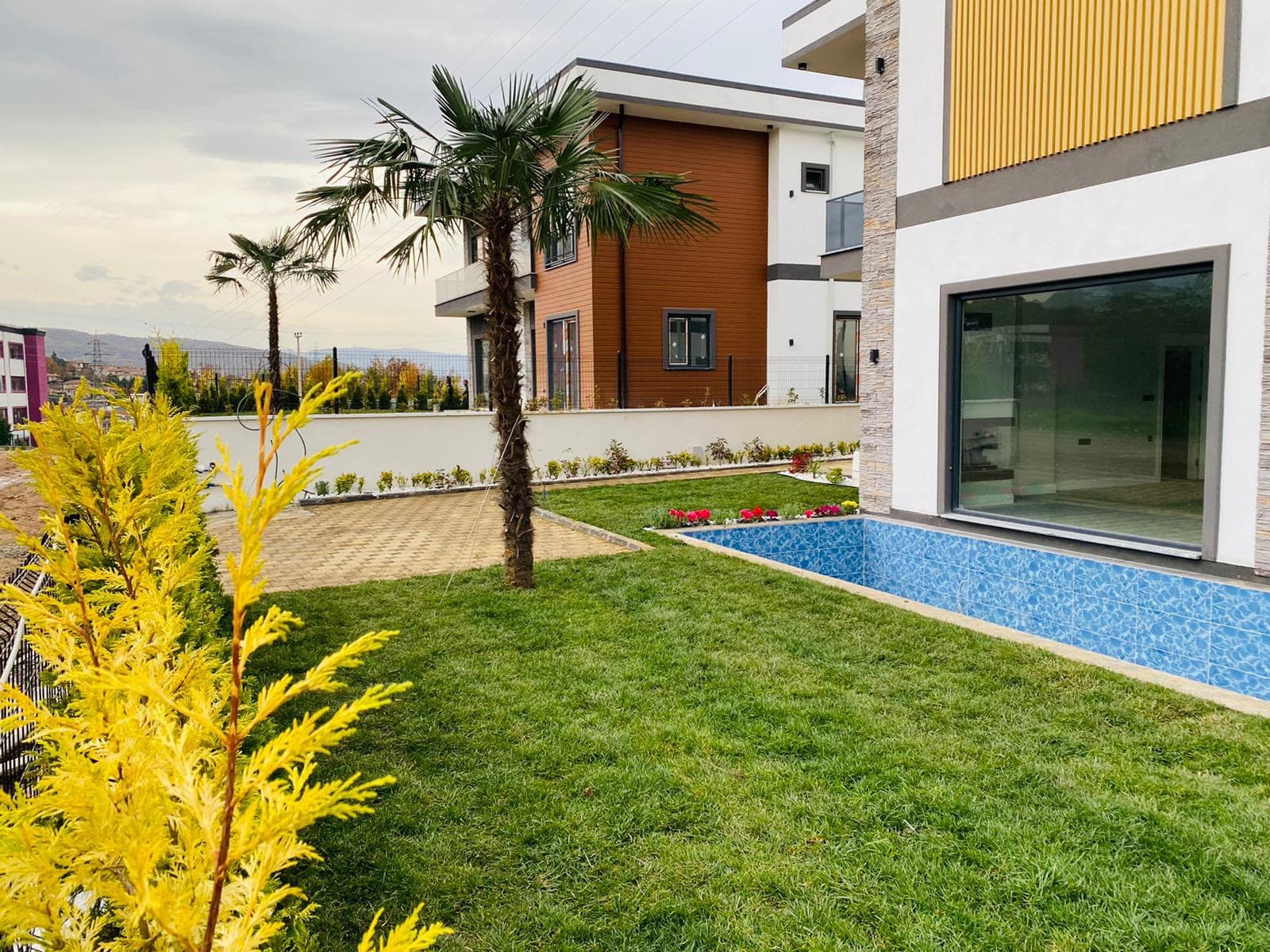 Modern villa bahçesinde palmiye ve özenle düzenlenmiş yeşil alan